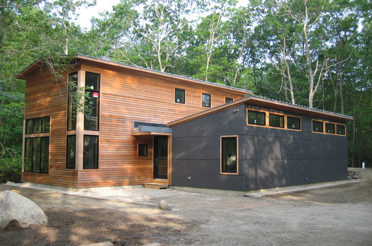 Modern home exterior with cedar and charcoal panel siding set among birch trees